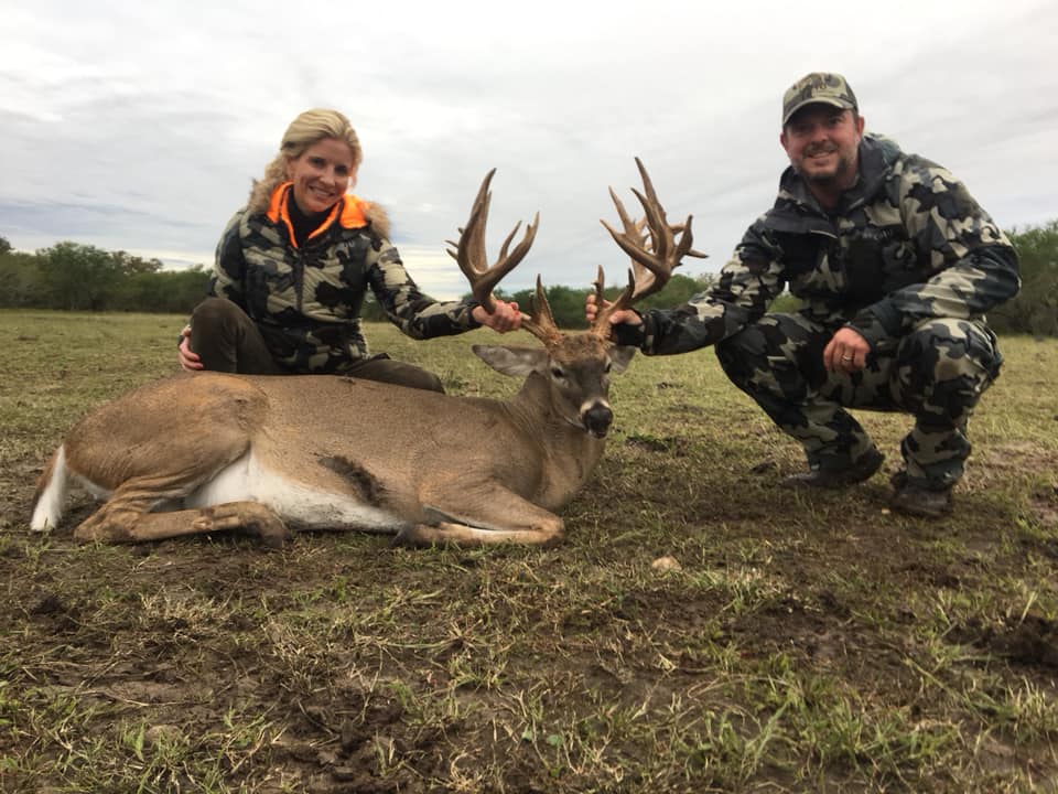Husband and wife enjoying their hunting success at the Austin Trophy Whitetails ranch. Standing behind their trophy deer.
