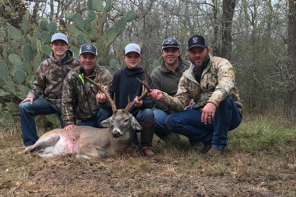 Five hunters surrounding their trophy deer at the ranch in Shiner, Texas.